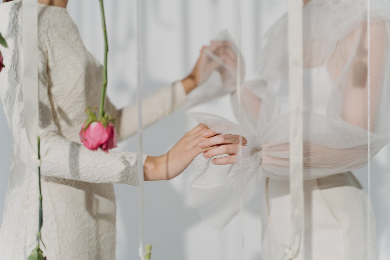 Artistic shot of two women in elegant white dresses with soft lighting.