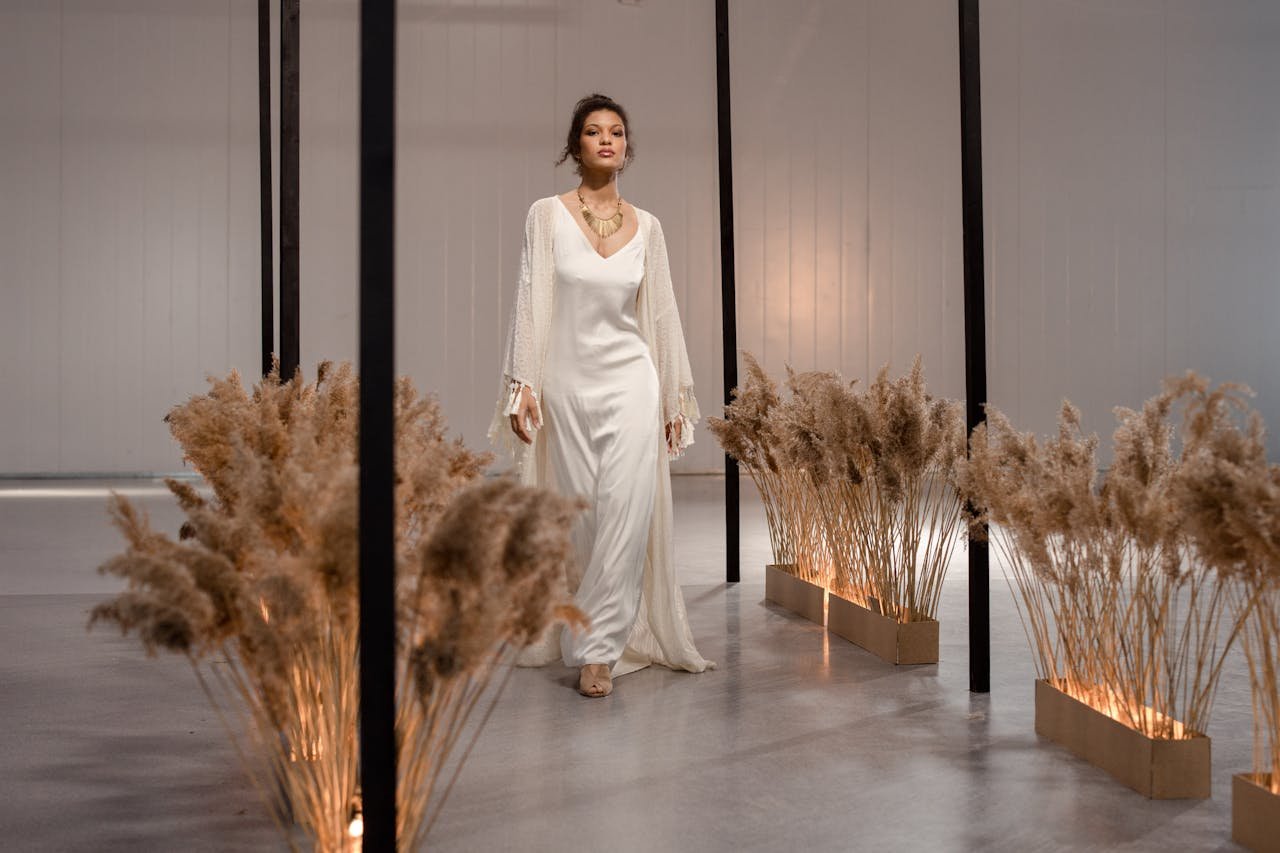 Model walks gracefully in a white gown amidst elegant decor, highlighting indoor fashion aesthetics.